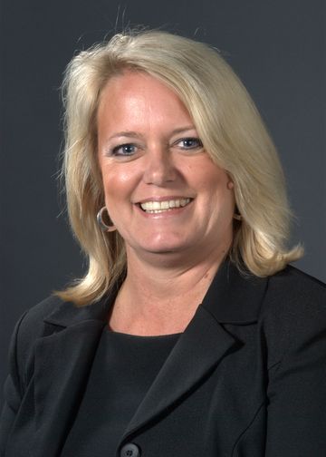 Carolyn Sweetapple, RN, PhD, wearing a dark suit